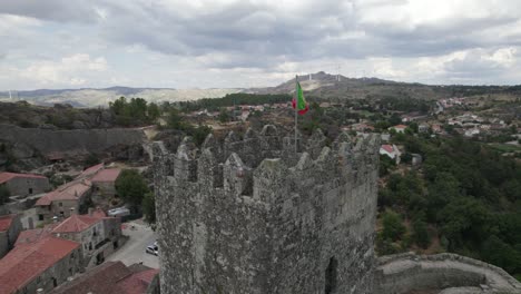 portuguese flag at hilltop towering castle of sortelha, portugal