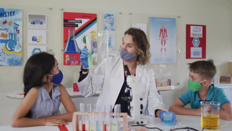 maestra con máscara facial y gafas de protección enseñando a los estudiantes en el laboratorio
