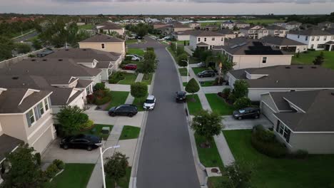 parking cars on street and driveway of well-kept housing area. sunset time in florida suburb. aerial birds eye shot. single family houses with palm trees in sun city, florida