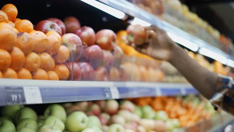 unrecognizable african american man standing in supermarket and choosing apples