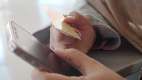 mujer que utiliza una tarjeta de crédito y un teléfono inteligente para el pago en línea
