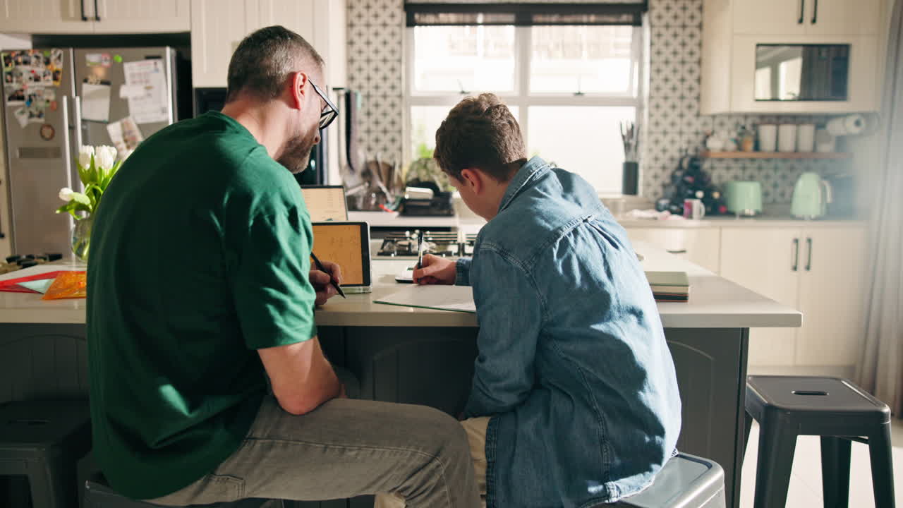 Father helping son with homework in the kitchen