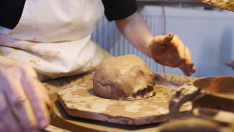 primer plano de un alfarero masculino arrojando arcilla para una olla en una rueda de cerámica en un estudio de cerámica
