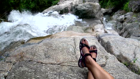 women's feet against the backdrop of a waterfall