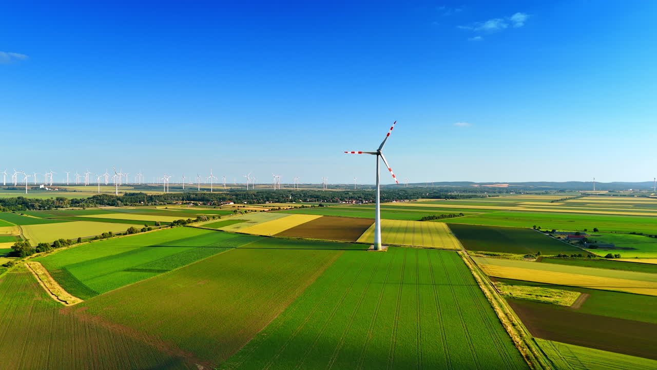 Wind turbine stands tall in green fields. A wind turbine rotates majestically above vibrant green fields under a clear blue sky in a rural landscape