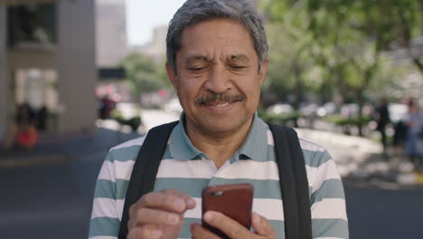 portrait-of-confident-senior-man-standing-in-street-texting-browsing-using-smartphone