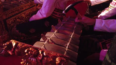 closeup hands of gamelan music player musical instrument, bali indonesia night temple ceremony