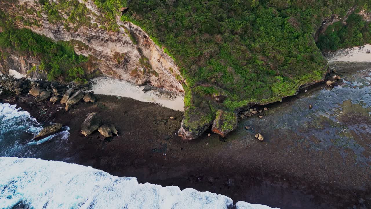 Drone footage showcases Nyang Nyang Beach in Uluwatu with steep cliffs, golden hour light, and a calm shoreline creating a serene tropical scene on Bali’s dramatic southern coast.