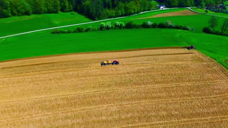 aerial view of farmers harvesting crops in golden field with green surroundings