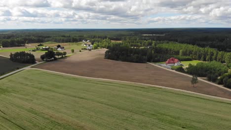 Aerial-view-of-a-small,-red-roofed-house-in-a-rural-area-of-Borowy-Młyn-in-Kaszuby,-Pomorskie-in-Poland