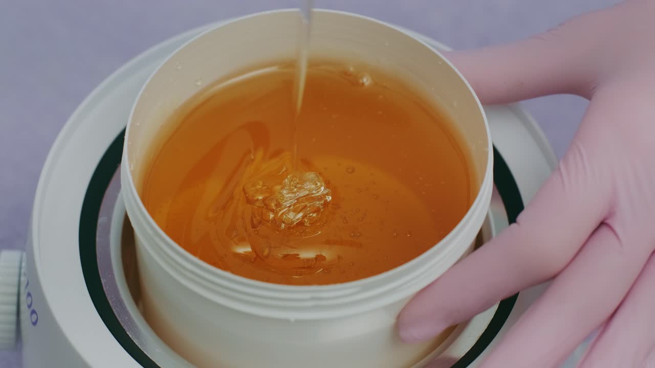 Liquid sugar for skin epilation. Close up shot. depilation and beauty concept - sugar paste or wax honey for hair removing with wooden waxing spatula sticks