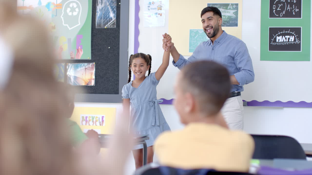 Teacher celebrates with a biracial girl in a classroom at school