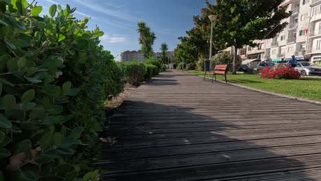 wooden street sidewalk with plants and garden on the sides in front of the village houses and people going about their daily lives in summer with sunny day
