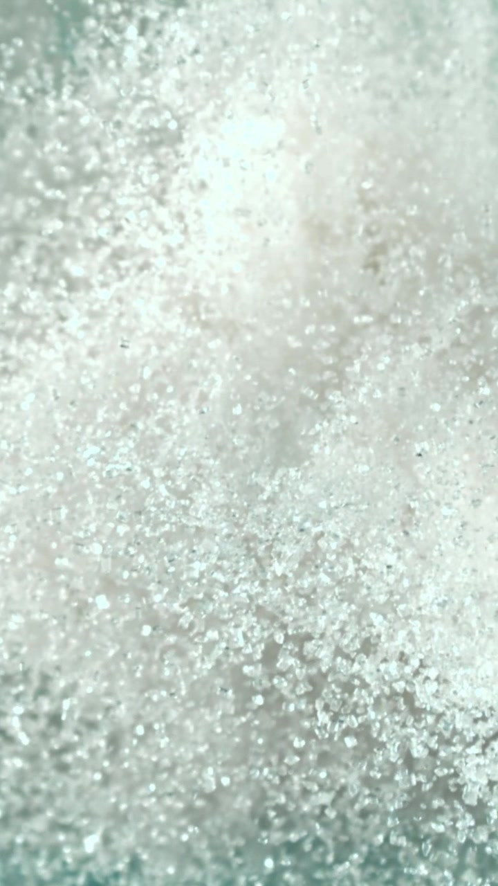 Macro di cristalli di zucchero bianco scintillanti in caduta