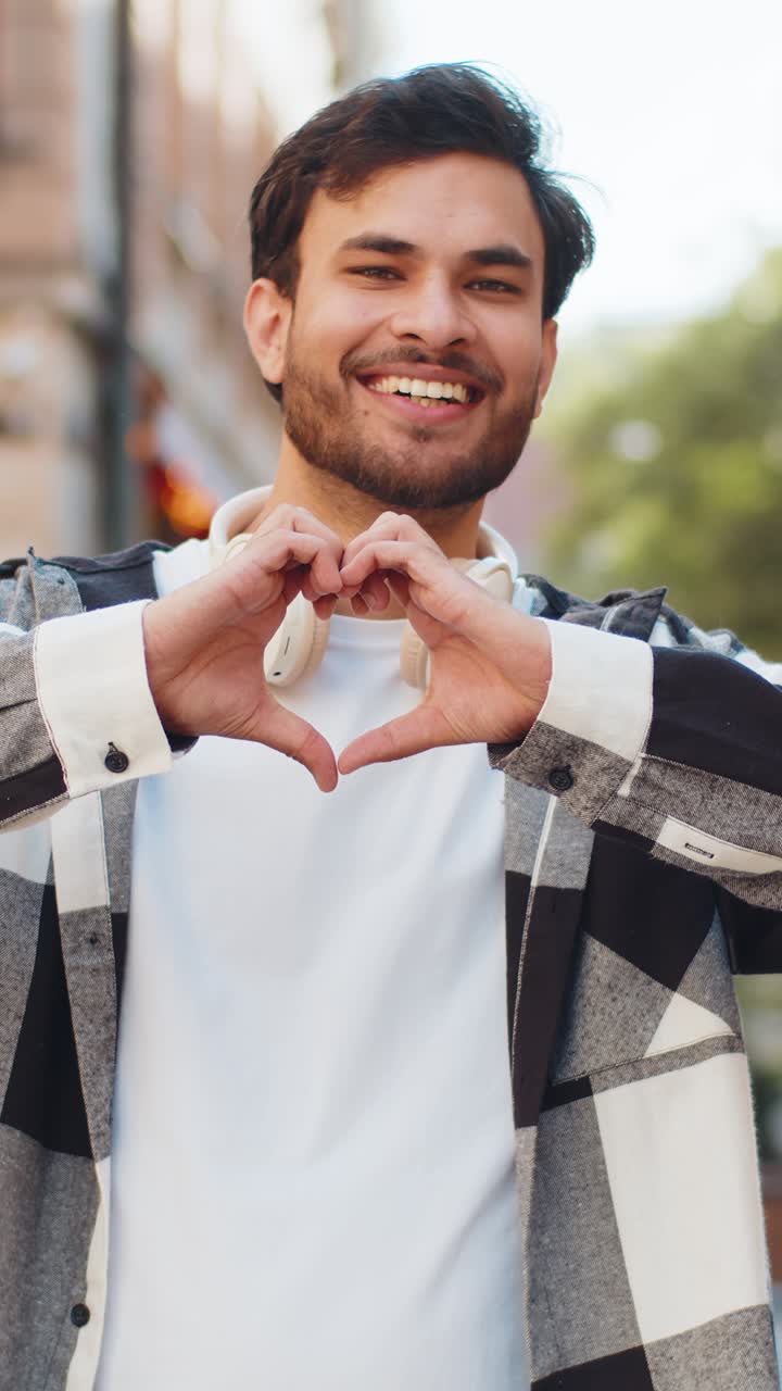 Indian man makes symbol of love showing heart sign to camera express romantic feelings on street
