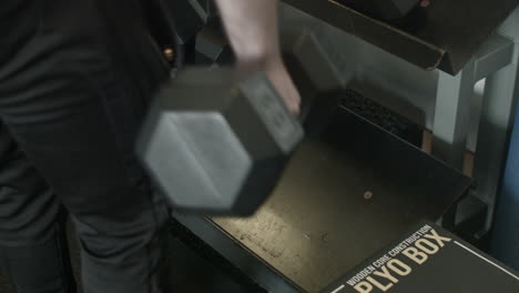 extreme close up of a man grabbing heavy dumbbells