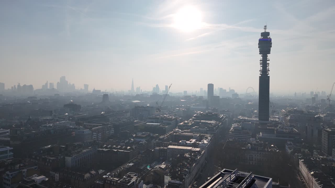 Drone push in London skyline and BT tower silhouetted against Low rising sun