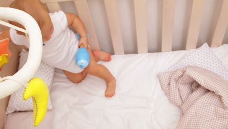 Cute-baby-girl-standing-up-in-her-cot-playing-with-mobile