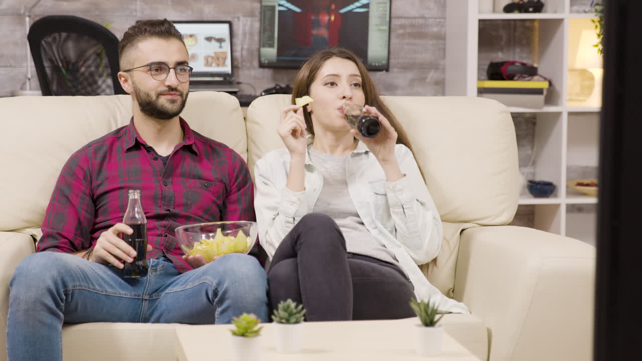 una pareja relajándose en casa viendo la televisión.