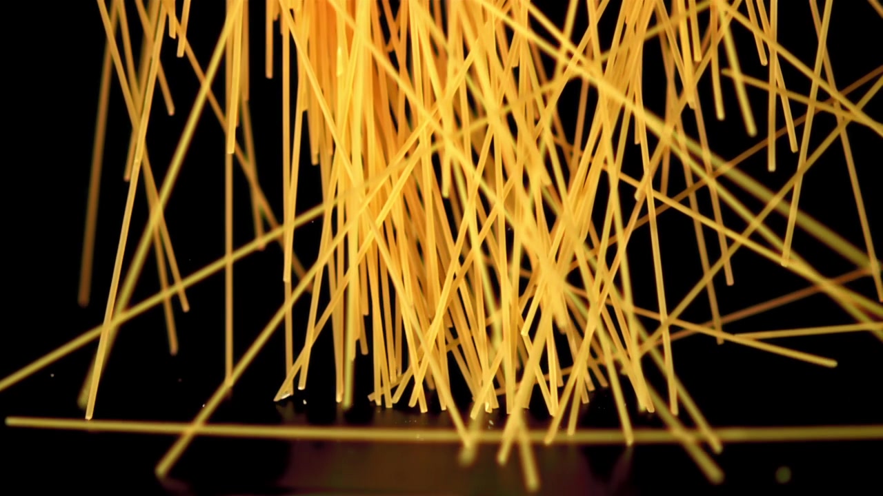 Spaghetti secchi che cadono su sfondo nero al rallentatore.