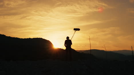 silhouette of a boom operator walking on the mountain nature at sunset