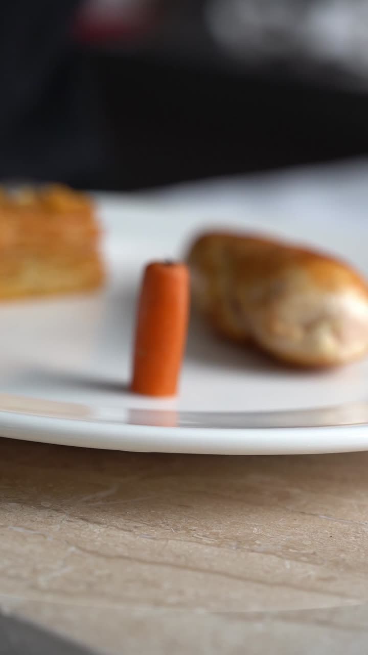 Chef emplatando un trozo de pollo asado con zanahorias y judías verdes en un plato, primer plano, toma de detalle