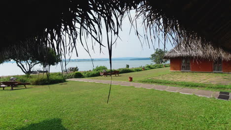 peaceful distant view of kabini river water from a riverside resort with a thatched hut during a hot day afternoon in karnataka, india. slow motion.