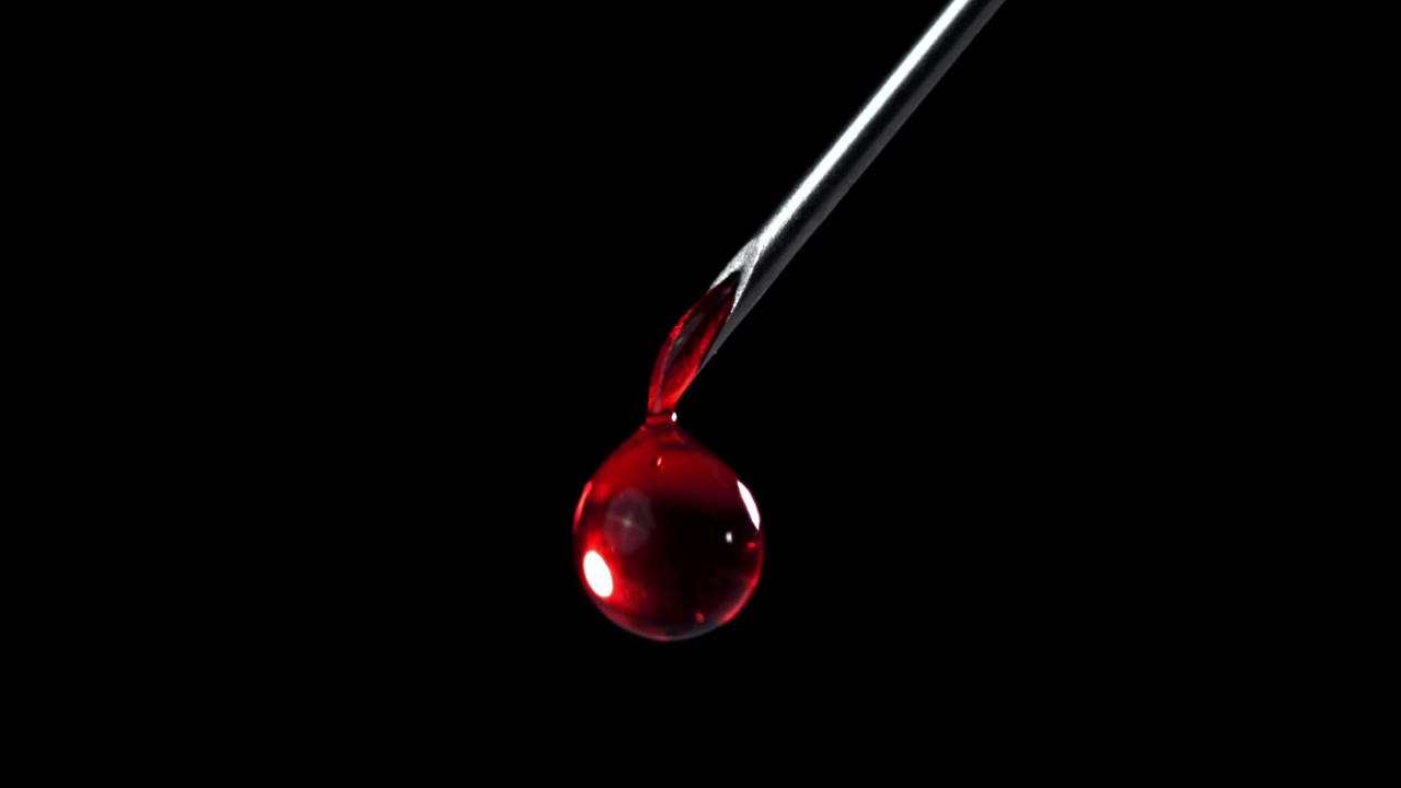 Roter Flüssigkeitstropfen tropft von einer medizinischen Nadelspitze