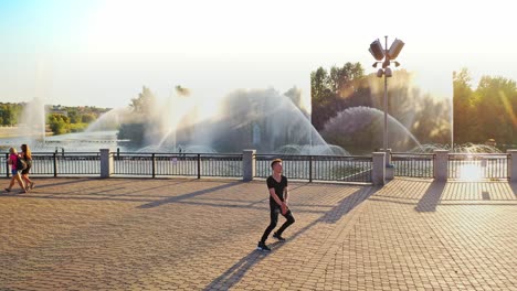 modern boy dancer is dancing in the street. urban lifestyle. hip-hop generation. boy's emotional moves on the video. paving stones and young man at fontain background. aerial view. young handsome professional dancer boy.