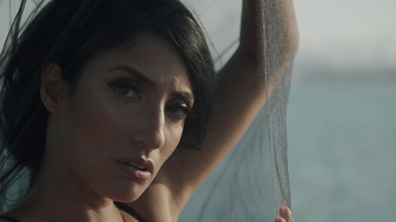 bella mujer posando con un chal de red en la cámara