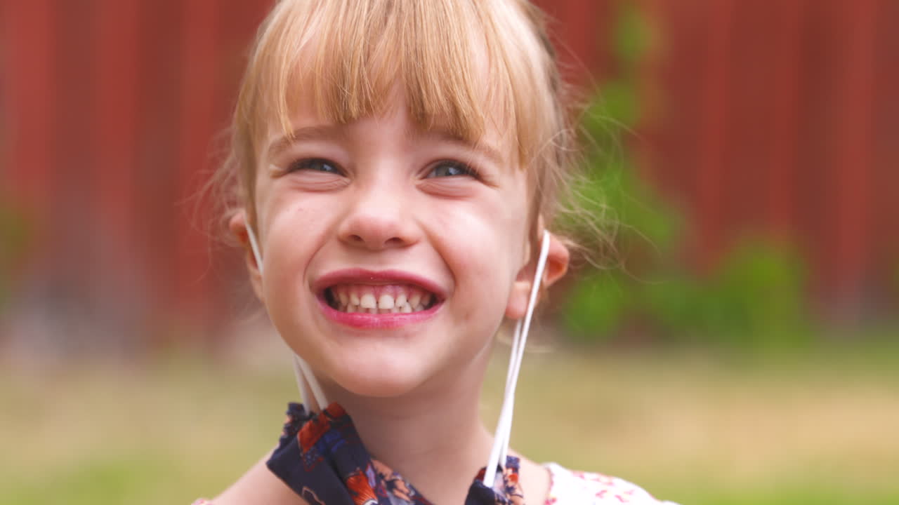 Menina feliz tira a máscara facial e sorri radiantemente