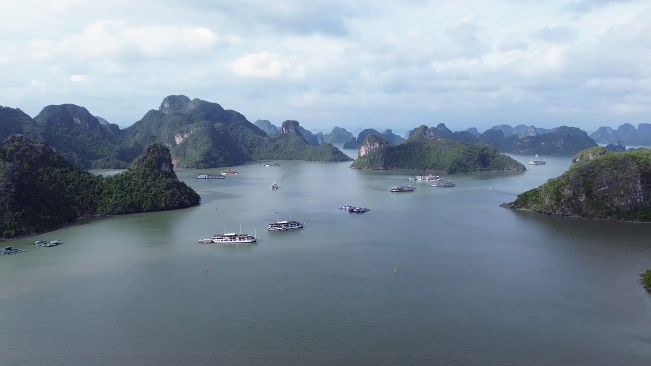 Semi orbit aerial showing tourist boats anchored in Cat Ba Bay, surrounded by limestone islets