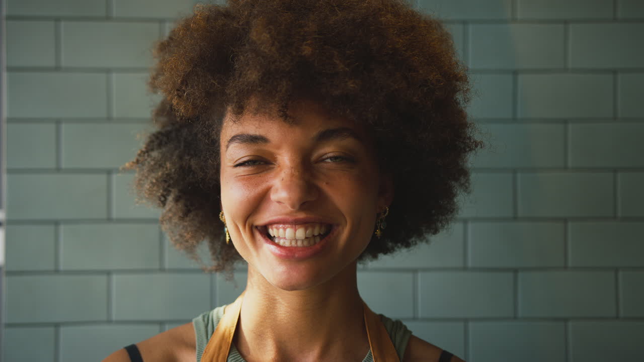 Portrait Of Laughing Female Owner Or Member Of Staff Wearing Apron Inside Shop Or Cafe