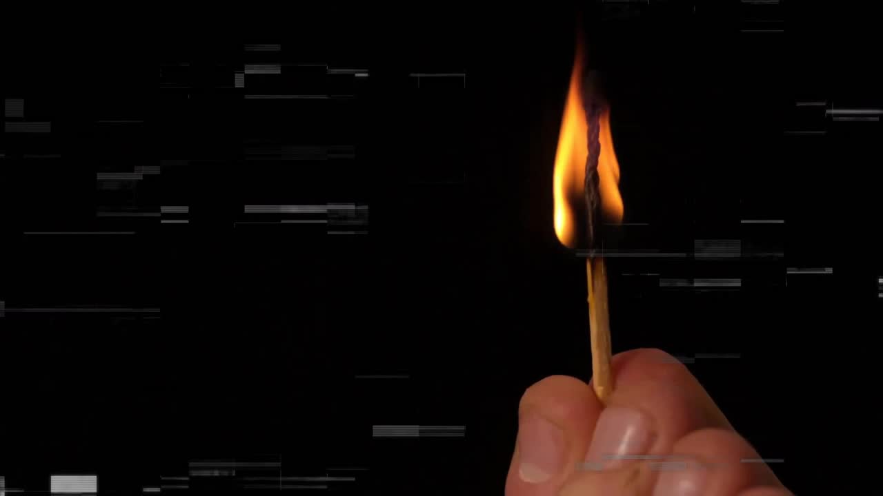 Une main allume une allumette, provoquant une flamme qui vacille, s'allonge et se rétrécit, montrant ainsi la combustion.