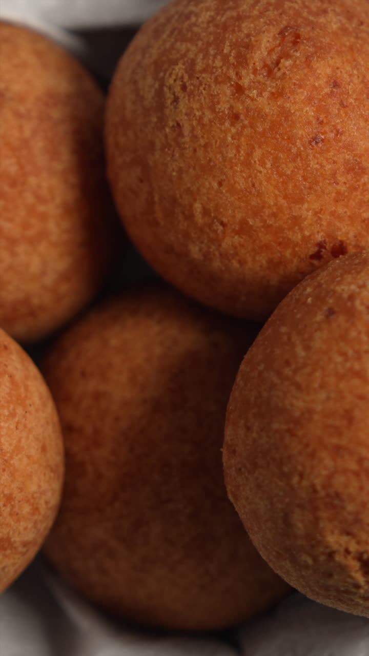 Delicious golden brown buñuelos stacked, highlighting their crisp texture in vertical video. Ideal for mobile, social media stories. Warm, inviting lighting enhances detail