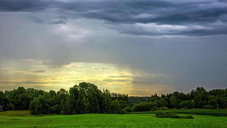 Zeitrafferaufnahme-Dunkler-Wolken,-Die-Am-Abend-Vorbeiziehen,-Umgeben-Von-Hohen-Bäumen-über-Grünem-Grasland