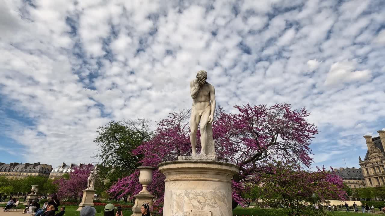 방문객들은 파리 정원에서 동상 주위에 모입니다.