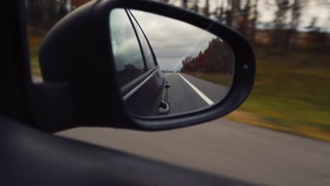 shoot in rear-view mirror of car at road under evening sunset.