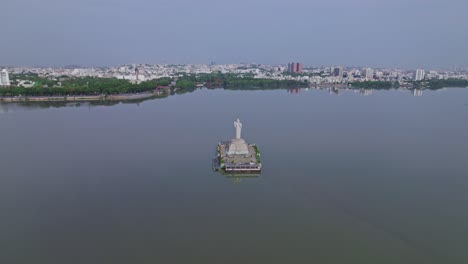 hussain sagar lake with buddha statue in background crowded building at tank bund, khairtabad, hyderabad, telangana, india. day time, push in, drone shot, 4k.
