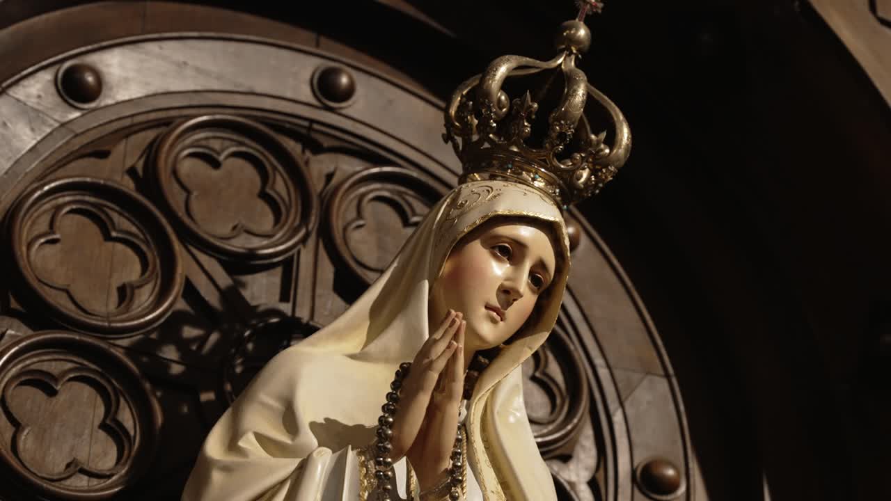 statue of crowned virgin mary in prayer with rosary and gentle lighting