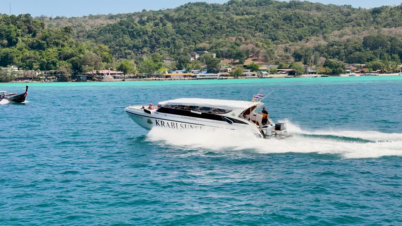 Un motoscafo bianco attraversa acque oceaniche di un blu brillante con lussureggianti isole tropicali alle spalle