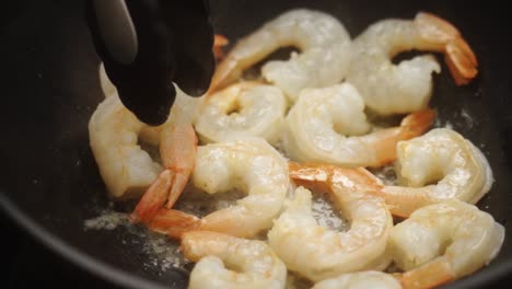 unrecognizable cook frying prawns in pan with hot oil