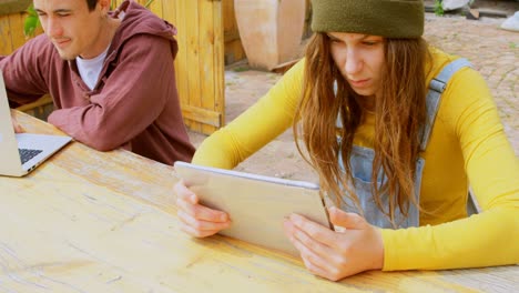 Front-view-of-stylish-young-caucasian-skateboarders-using-multimedia-devices-at-outdoor-cafe-4k