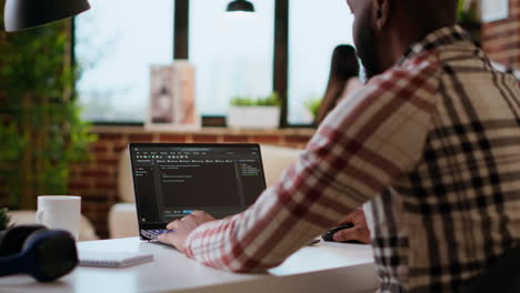 ingegnere software afroamericano che lavora su un portatile e scrive il codice di un progetto.