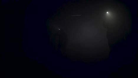 people exploring a dark cave with headlamps