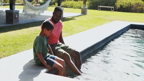 father and son sitting on the edge of the pool