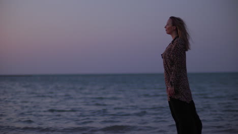 a beautiful young woman on the windy beach at sunset