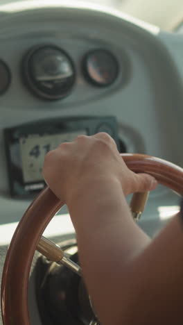 young skipper holds luxury yacht helm standing in cockpit closeup. man sails motor boat travelling in sea on sunny day. captain of vessel ship