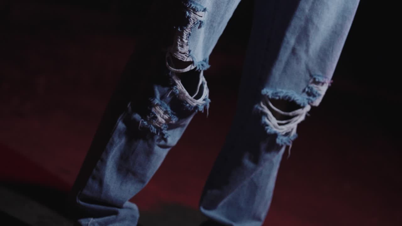 Young beautiful woman in ripped jeans on the street at night