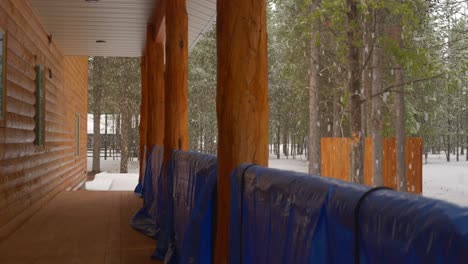 lado de la cabaña nevado por una fuerte pero lenta tormenta de nieve en medio de los bosques de pinos